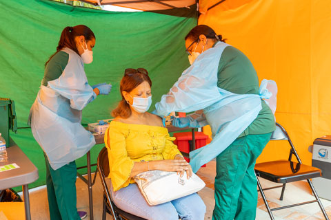  UHealth registered nurse Barbara Terras gives Hialeah resident Martha Ferran her COVID-19 vaccine, as UHealth registered nurse Diana Mejías assists her. Photos: Evan Garcia/University of Miami 
