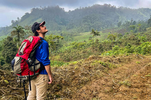  Botanist and graduate student Riley Fortier admires the plantations, pastures, and remnants of old cloud forest that cover Centinela Ridge in coastal Ecuador. Photo by Dawson White 
