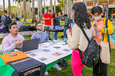  From left, students Andres Florez and Miguel Silveira speak with their peers about the Association of Commuter Students during an involvement fair on the Foote Green. 